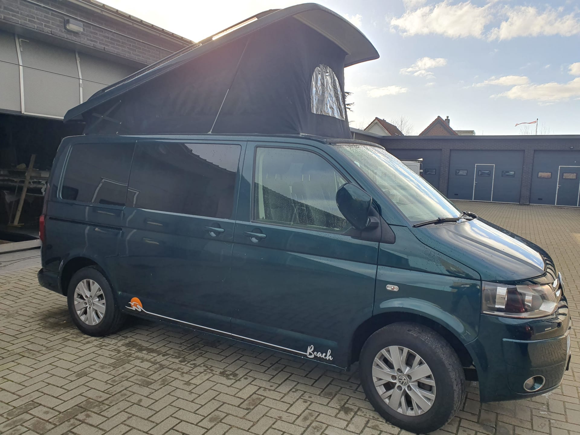 Volkswagen camper geparkeerd in een weids landschap bij zonsondergang
