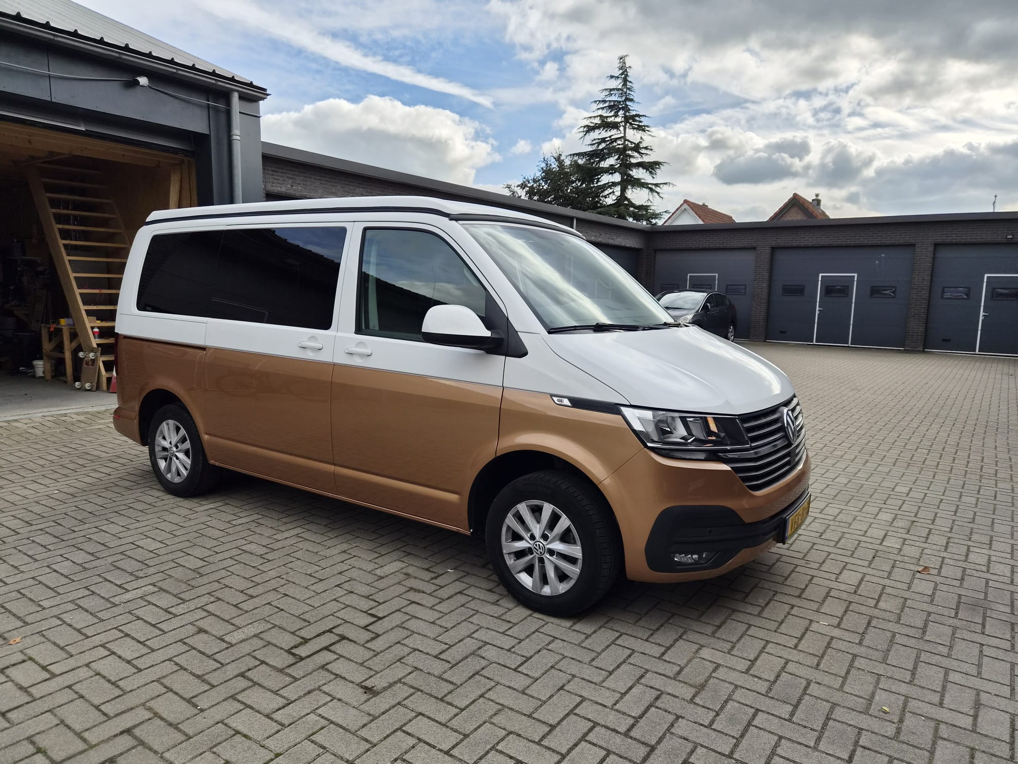 Wit en bronzen Volkswagen T6.1 buscamper op het terrein van Bencampers